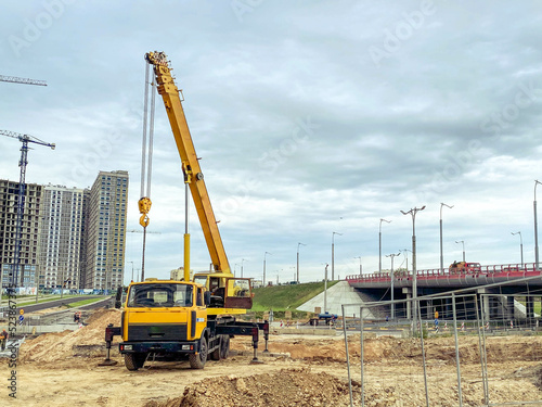 construction machinery builds a large residential area. construction of houses from blocks, glass. yellow heavy truck lifts heavy concrete slabs for house construction