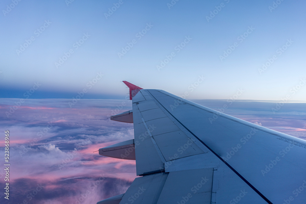 Wispy Pink clouds at dusk beneath commercial planes wing  - Centred with Copy Space