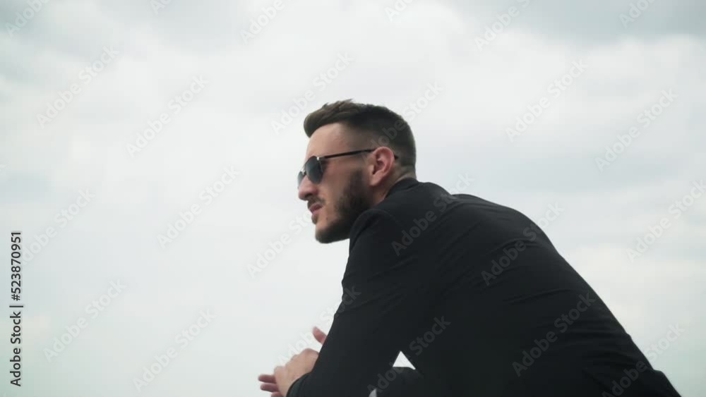 Bearded handsome businessman in suit in sunglasses looks into the distance Bearded handsome businessman in suit in sunglasses looks into the distance
