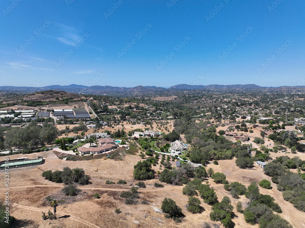 Aerial view of dry valley and land with houses and barn in Escondido, San Diego, California