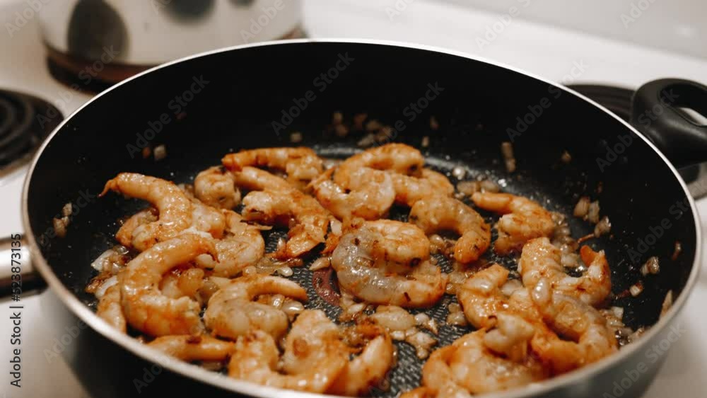 Shrimps are fried in a pan. Preparing pasta with shrimp in a creamy sauce with onions. Shrimps are fried in a pan. Preparing pasta with shrimp in a creamy sauce with onions.