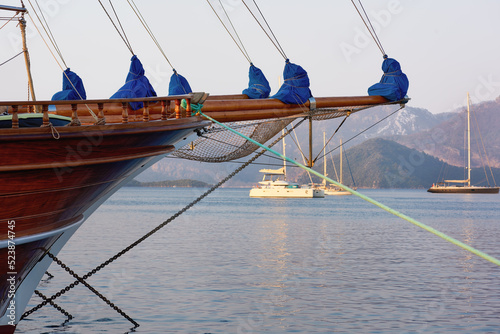 Wooden prow of a sailing ship. Bowsprit with tight ropes. Moored ship at anchor overlooking the sea bay. Marmaris. Turkey.