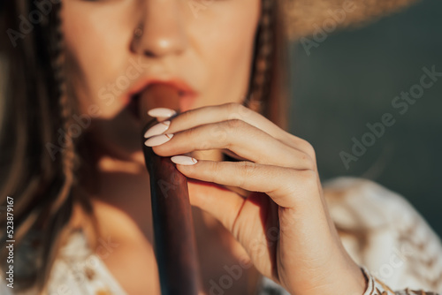 Woman playing on woodwind wooden flute - ukrainian telenka or tylynka in wheat field. Folk music concept. Musical instrument. Musician in traditional embroidered shirt - Vyshyvanka. photo