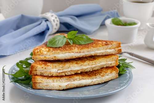 Stack of sliced fried sandwich with melted mozzarella on a plate. Italian grilled cheese sandwich Mozzarella in carrozza on white stone background. photo
