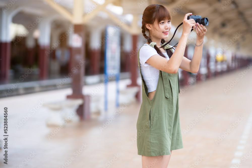 Fototapeta premium Portrait Young asian woman smiling tourist Traveler girl walking and with a holding the camera waits train travel journey is taken in railway platform Thailand, summer relax vacation Concept.