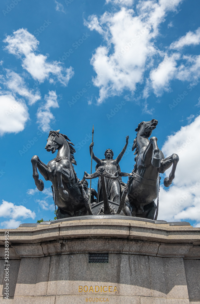 London, UK - July 4, 2022: Frontal closeup of Boudiccan Rebellion statue showing Celtic Queen attacking with a horse span under blue cloudscape. NW corner of Westminster bridge