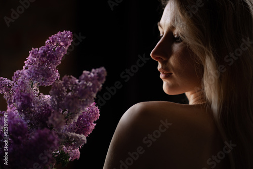 Obraz na plátně profile of a beautiful blonde woman with a bare shoulder and a bouquet of lilacs