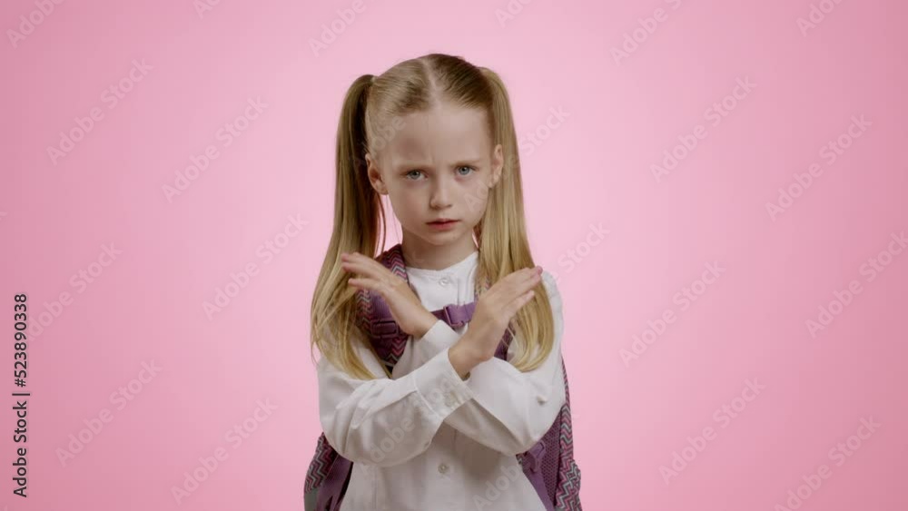 Stop bullying at school. Llittle upset schoolgirl with backpack crossing her hands in denial, expressing negativity Stop bullying at school. Llittle upset schoolgirl with backpack crossing her hands in denial, expressing negativity