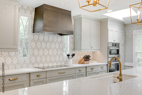 Obraz na płótnie Luxury interior staged kitchen white stone countertops decor stools ceramic tile backsplash modern brass light pendants wood columns w salonie