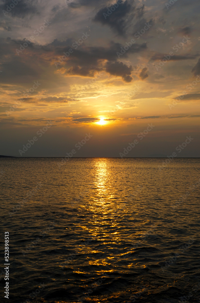 Beautiful sundown above golden sea surface in warm color tones