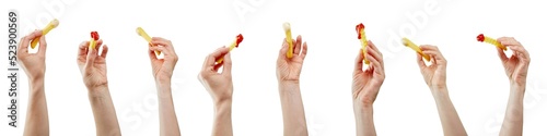 Hands holding the French fries with ketchup and white sauce in front of the white background