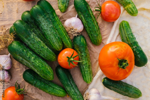 Fresh vegetables on a wooden background. The concept of healthy eating. Cucumbers, tomatoes, garlic, dill. Top view.