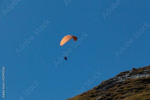 Low angle shot of a paraglider flying over the Alps in Canazei, Italy