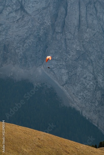 Vertical shot of a paraglider flying over the Alps in Canazei, Italy photo
