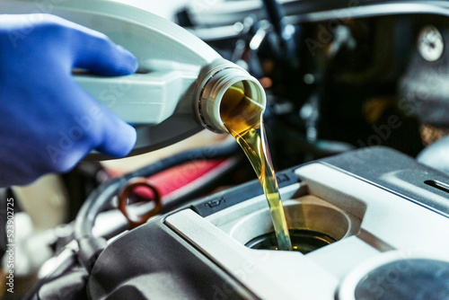 automobile oil is poured into the engine close up. pouring new oil into the engine. car engine oil change