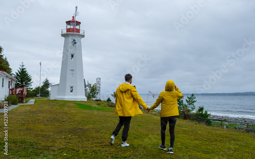 Quadra Island old historical lighthouse at Cape Mudge Vancouver Island, Canada. couple in yellow raincoats during the storm by the coast of Vancouver Island.  photo