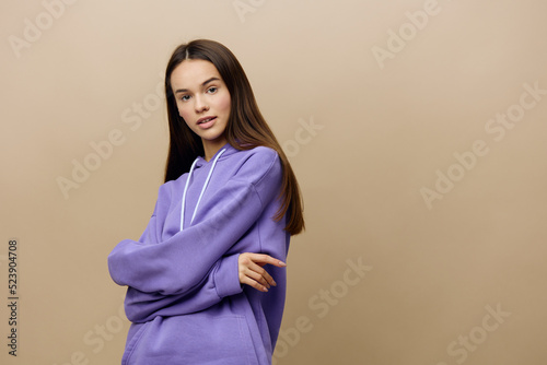 a beautiful, pleasant, thoughtful woman stands on a beige background in a purple suit with her arms crossed on her chest and looks into the camera © Tatiana