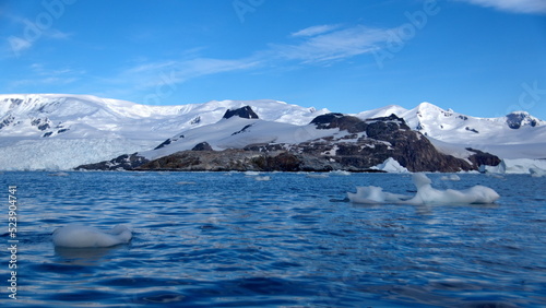 Icebergs floating at the base of snow covered mountains in Cierva Cove, Antarctica © Angela