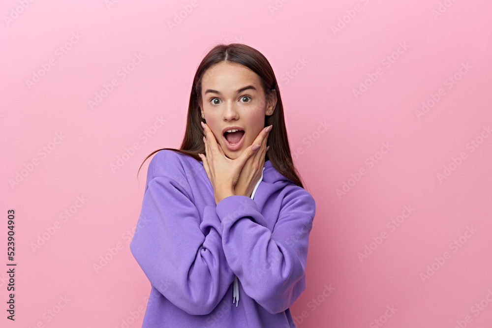 a very emotional, sad, shocked woman stands on a pink background in a lilac stylish tracksuit and holds her hands near her face a very emotional, sad, shocked woman stands on a pink background in a lilac stylish tracksuit and holds her hands near her face