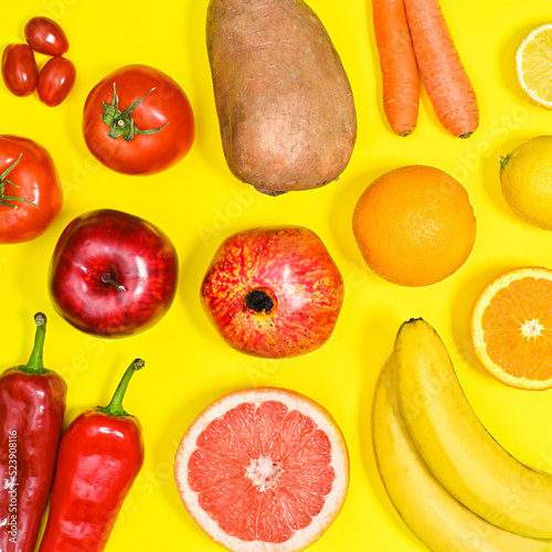 Yellow brackground with summer fruits and vegetables in colors from red to yellow. Flat lay pattern
