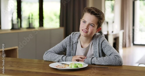 Unhappy child eating a healthy meal with vegetables at home and refusing to eat his greens. Little boy showing disgust and being fussy about dinner, lunch food. Picky eater making facial expression photo