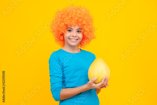 Teenager child girl hold citrus fruit pummelo or pomelo full of vitamin  isolated on yellow background. Kid healthy eating. Happy teenager portrait. Smiling girl.