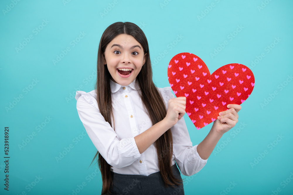 Cheerful lovely romantic teen girl hold red heart symbol of love for valentines day isolated on blue background. Cheerful lovely romantic teen girl hold red heart symbol of love for valentines day isolated on blue background.