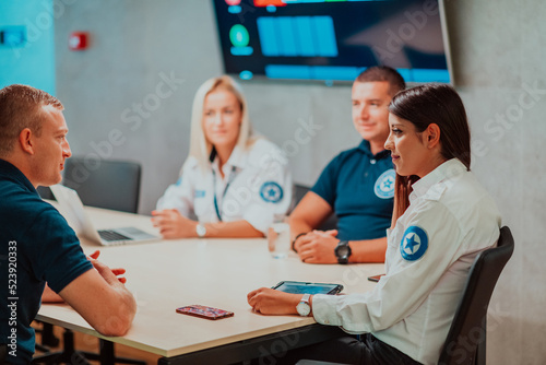Group of security guards sitting and having briefing In the system control room They re working in security data center surrounded by multiple Screens