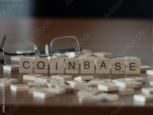 coinbase word or concept represented by wooden letter tiles on a wooden table with glasses and a book photo