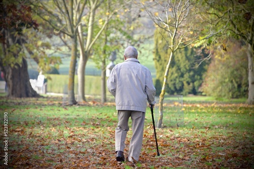 Elderly man from behind walking in a park in fall photo