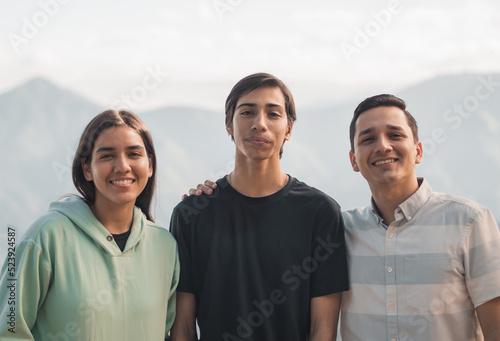 portrait of 3 siblings on vacation in the highlands of Ecuador, smiling with the younger brother in the middle, selective focus on the subject in the center.