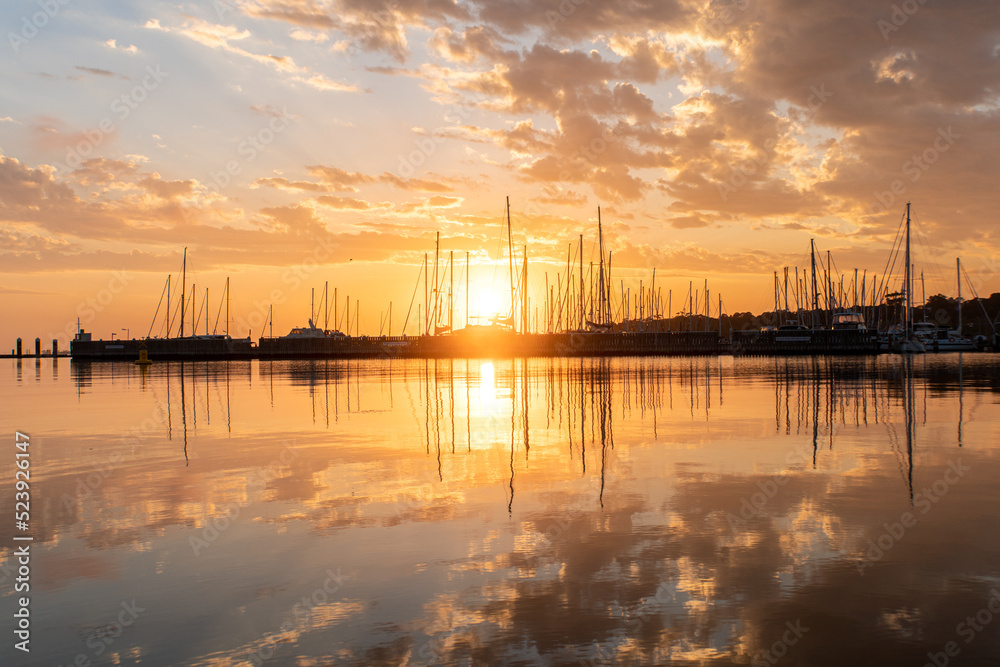 Clouds and yacht masts reflected in calm waters at Geelong waterfront