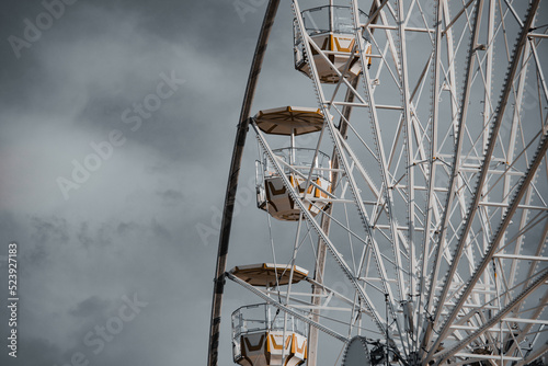 Fototapeta Naklejka Na Ścianę i Meble -   close up top part of ferris wheel with cabins against dramatic sky