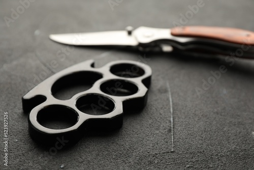 Fotografie Brass knuckles and knife on black stone background, closeup