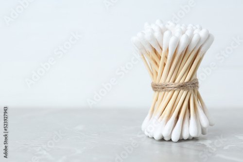 Many cotton buds on light grey marble table  space for text