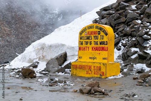 Sign on Khardung La, over a background of snowy rocks, India photo