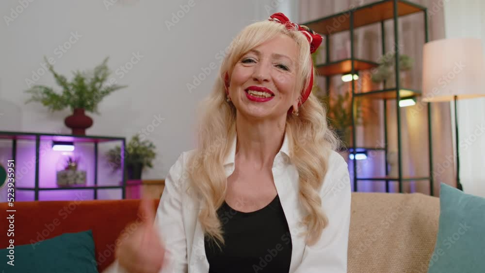 POV of senior old grandmother sitting on couch, looking at camera, making video webcam conference call with friends or family enjoying pleasant conversation. Woman laughing, waving hello alone at home
