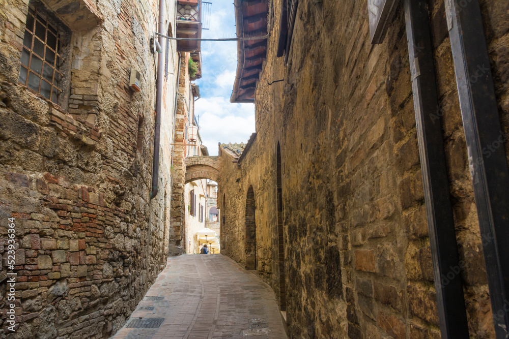 Narrow street and stone wall in the medieval city of San Gemignano, Tuscany, Italy.