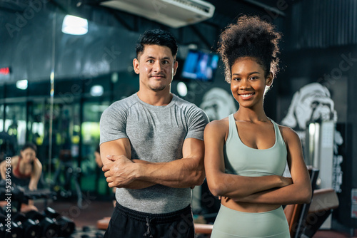 Portrait of African American woman and Caucasian man exercise in gym. 
