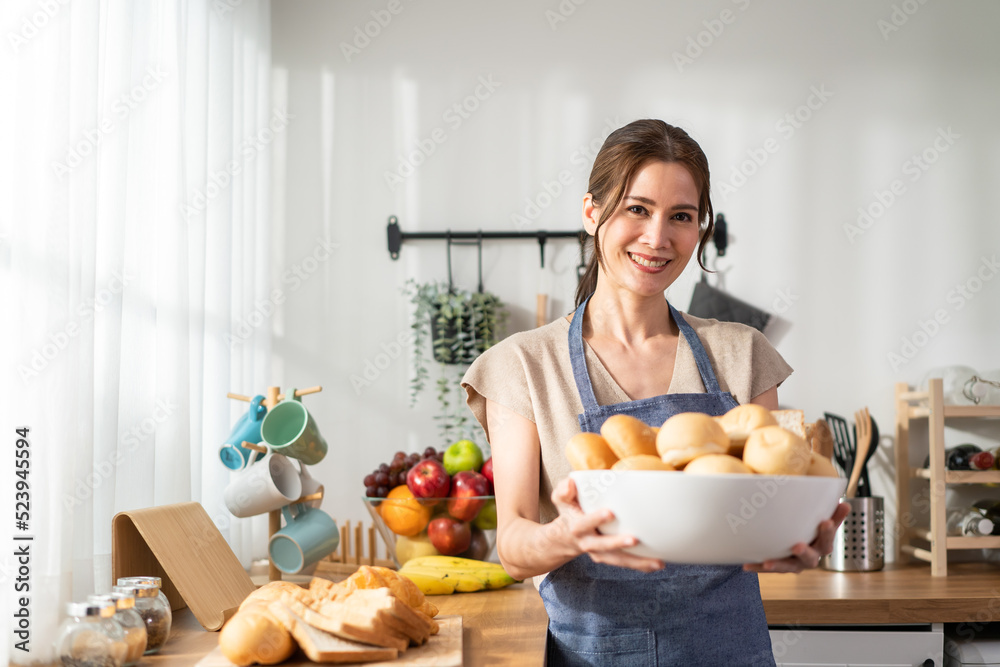 Portrait of Asian young woman hold a bowl of bread and look at camera. 