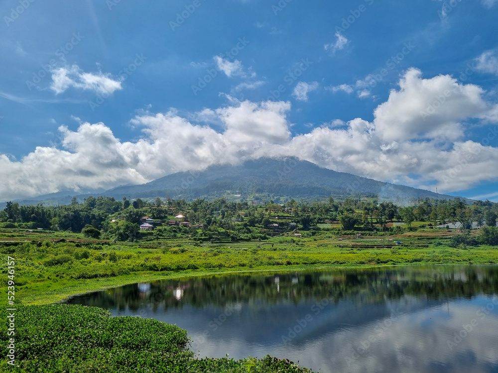 Beautiful reflection view of mountain from lake with blue sky background at west sumatera