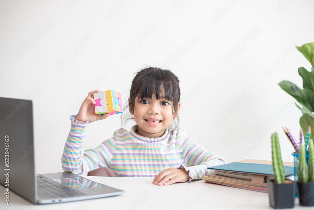 NAKHON RATCHASIMA, THAILAND - JULY 14, 2022:Asian little cute girl holding Rubik's cube in her hands. Rubik's cube is a game that increases the intelligence of children. NAKHON RATCHASIMA, THAILAND - JULY 14, 2022:Asian little cute girl holding Rubik's cube in her hands. Rubik's cube is a game that increases the intelligence of children.