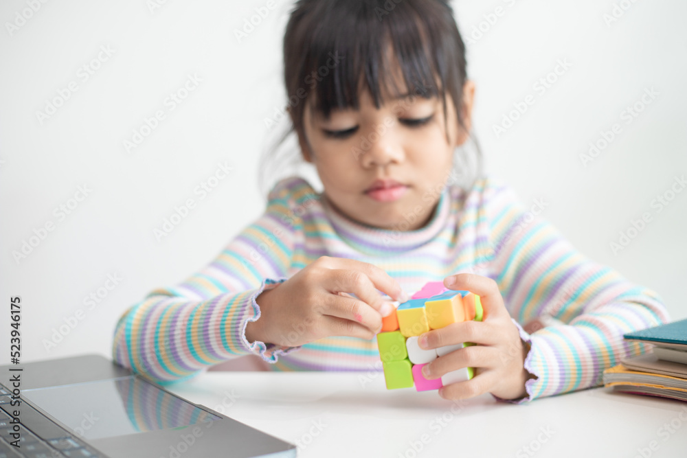 NAKHON RATCHASIMA, THAILAND - JULY 14, 2022:Asian little cute girl holding Rubik's cube in her hands. Rubik's cube is a game that increases the intelligence of children. NAKHON RATCHASIMA, THAILAND - JULY 14, 2022:Asian little cute girl holding Rubik's cube in her hands. Rubik's cube is a game that increases the intelligence of children.