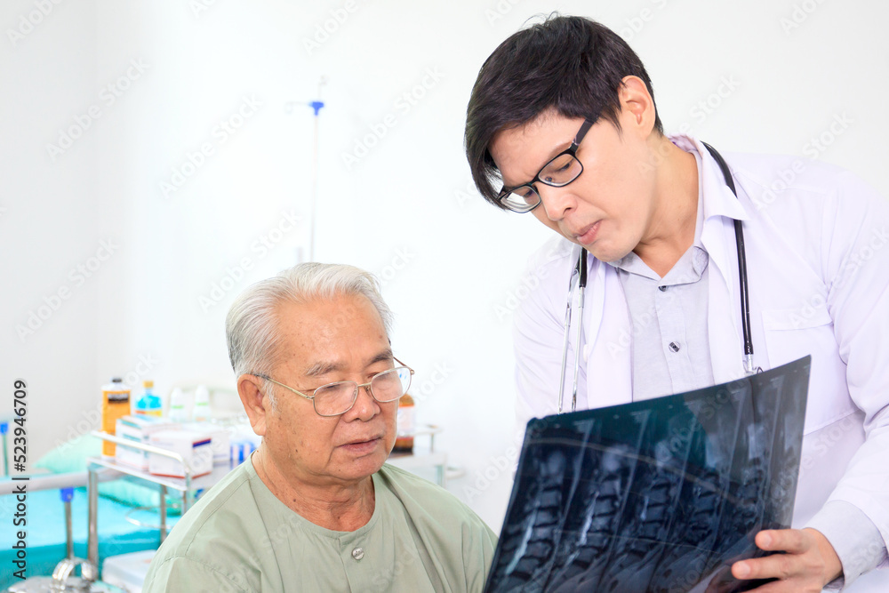 Obraz premium Asian elder adult having a consult with doctor about his disease, doctor explains the x-ray film to Asian senior adult. Health care and wellness in aging society.
