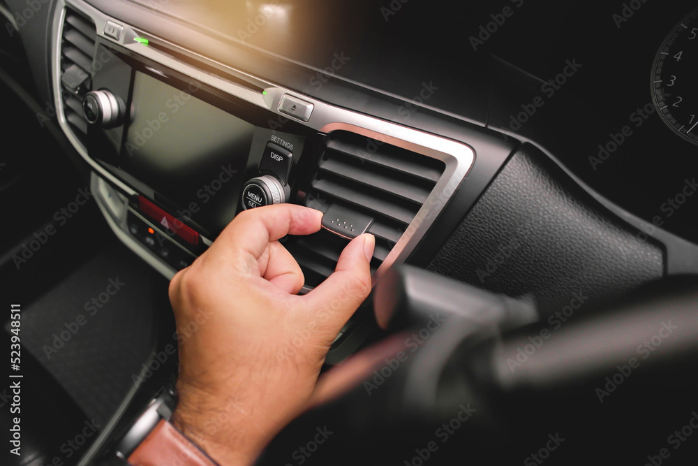 The driver hand adjusts the wind direction of the car air vent in the car.