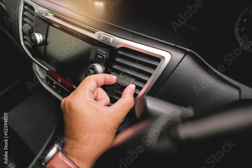 The driver hand adjusts the wind direction of the car air vent in the car.