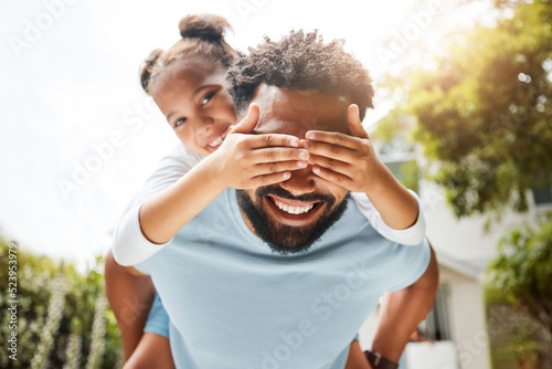Fun father playing with his young daughter on his back in their family home garden bonding together. Small child laughing and enjoying happy, silly childhood lifestyle with loving parent