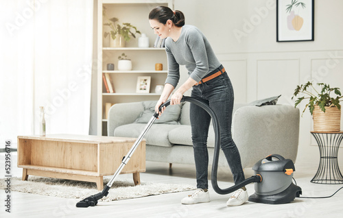 Vacuuming, cleaning and housework done by a mother, house wife or girlfriend using a vacuum cleaner. Stay at home mom, maid or housekeeper doing household chores and tidying in a modern living room