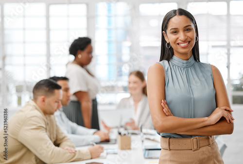 Smiling  happy and motivated young business woman with arms crossed showing great leadership to her team in an office. Portrait of confident and proud entrepreneur satisfied with growth in a startup