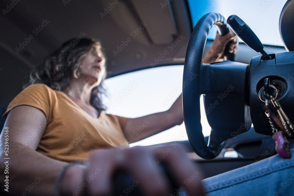 Hispanic adult female driving a car on the road with her hand on shift. Low angle view. Copy space.